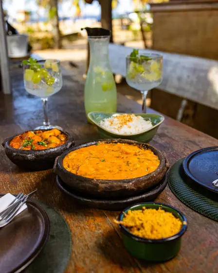 Panela de barro com creme de camarão, arroz, farofa e acompanhamentos