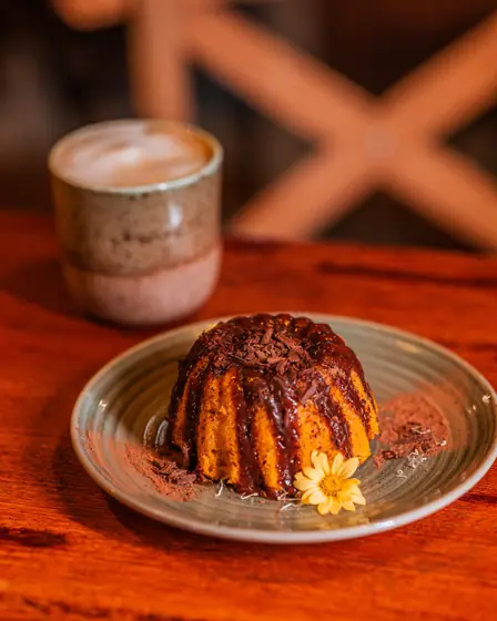 Bolo de cenoura com calda de chocolate e um café