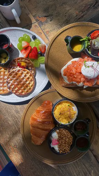 Café da manhã com croissant, ovos mexidos, frutas, granola e waffle