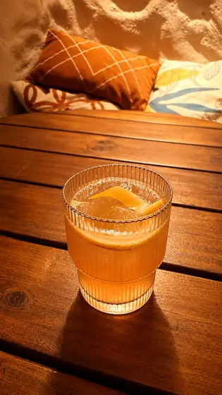 Drink alaranjado com gelo em copo canelado