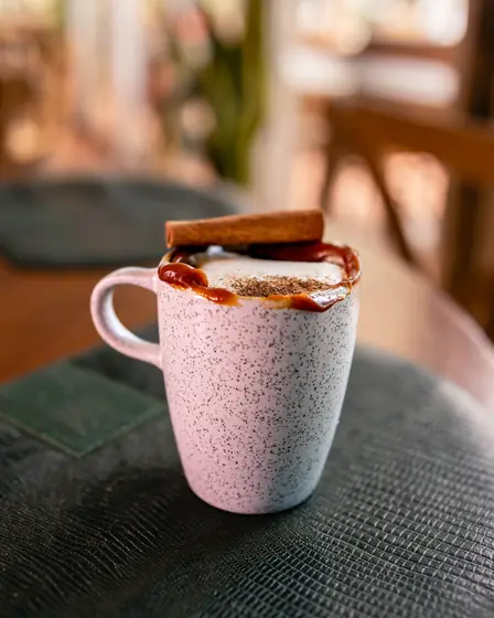 Caneca de café com leite, calda e canela em pau