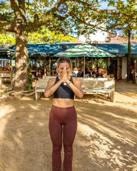 Professora de yoga na areia, sob a castanheira, em frente ao Clericot